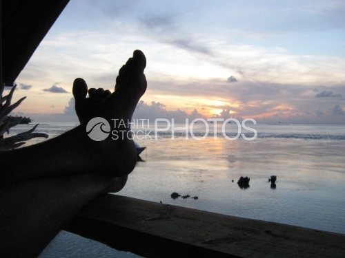 Pieds sur le bord du balcon, lors du coucher de soleil sur la mer, Tuamotu