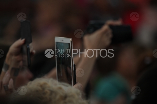 Mains portant un smartphone, prenant des clichés, en public