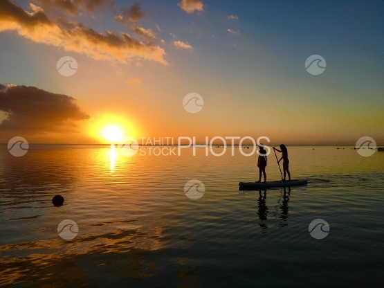 Moorea, Deux enfants pagayant à travers le coucher de soleil sur la plage de Hauru 