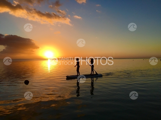 Moorea, Deux enfants pagayant à travers le coucher de soleil sur la plage de Hauru