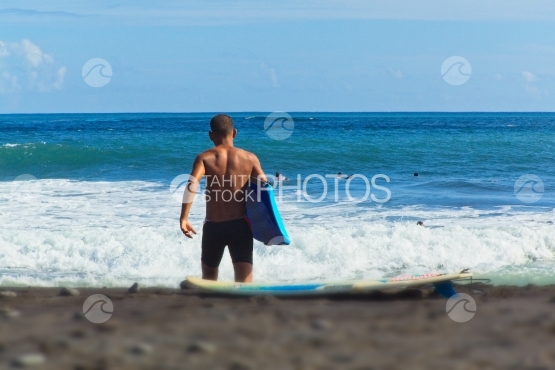 Tahiti, jeune allant surfer les vagues