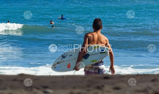 Tahiti, jeune allant surfer les vagues