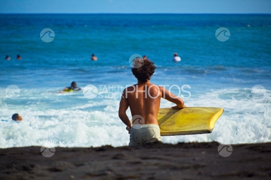Tahiti, jeune allant surfer les vagues