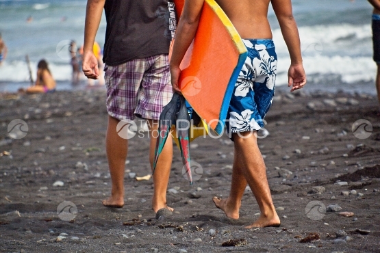 Tahiti, deux jeunes marchant sur la plage avec leurs body board