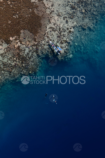 Chasseurs sous marin près du récif de corail, et pirogue, Polynésie